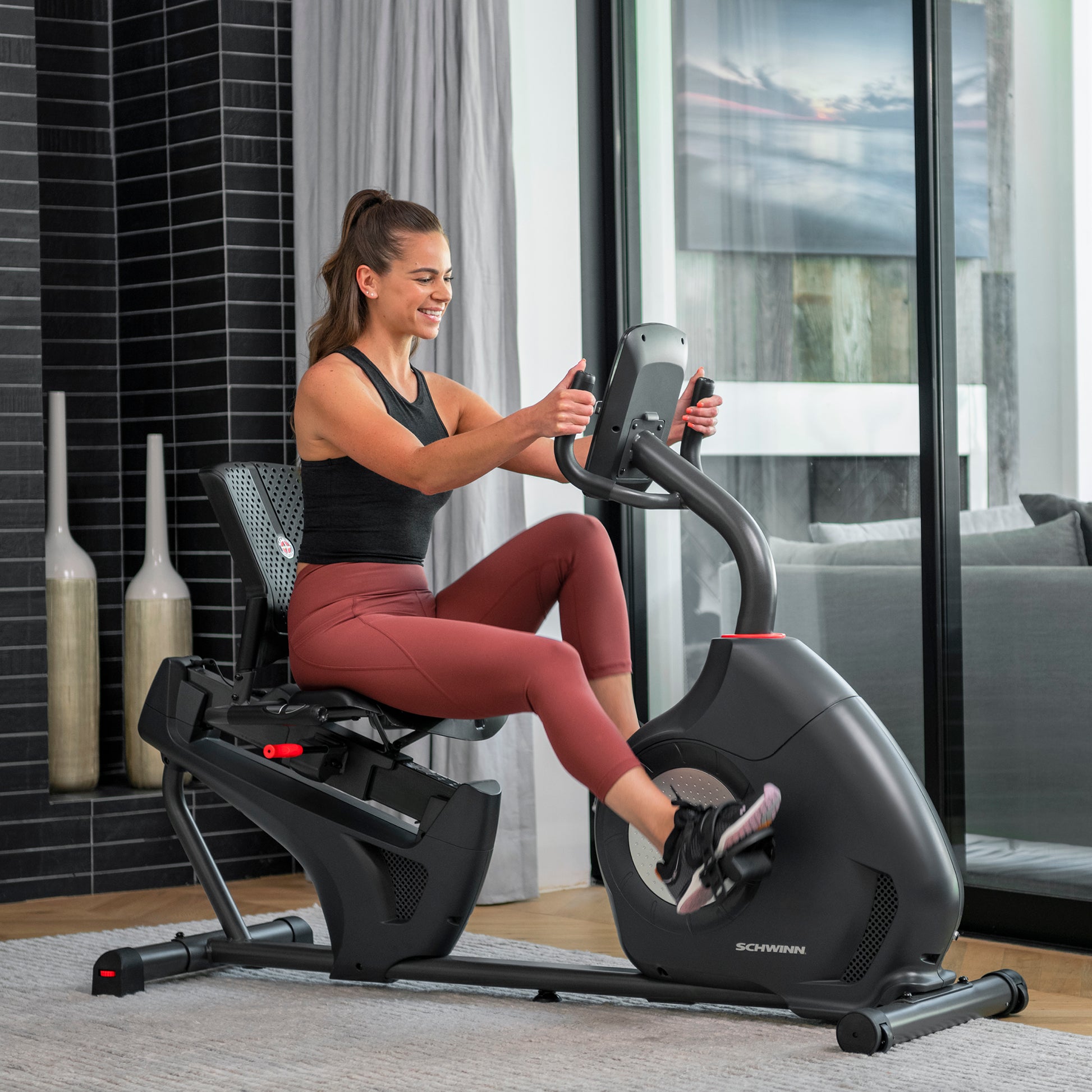 Woman exercising on a Schwinn recumbent bike in a home setting.