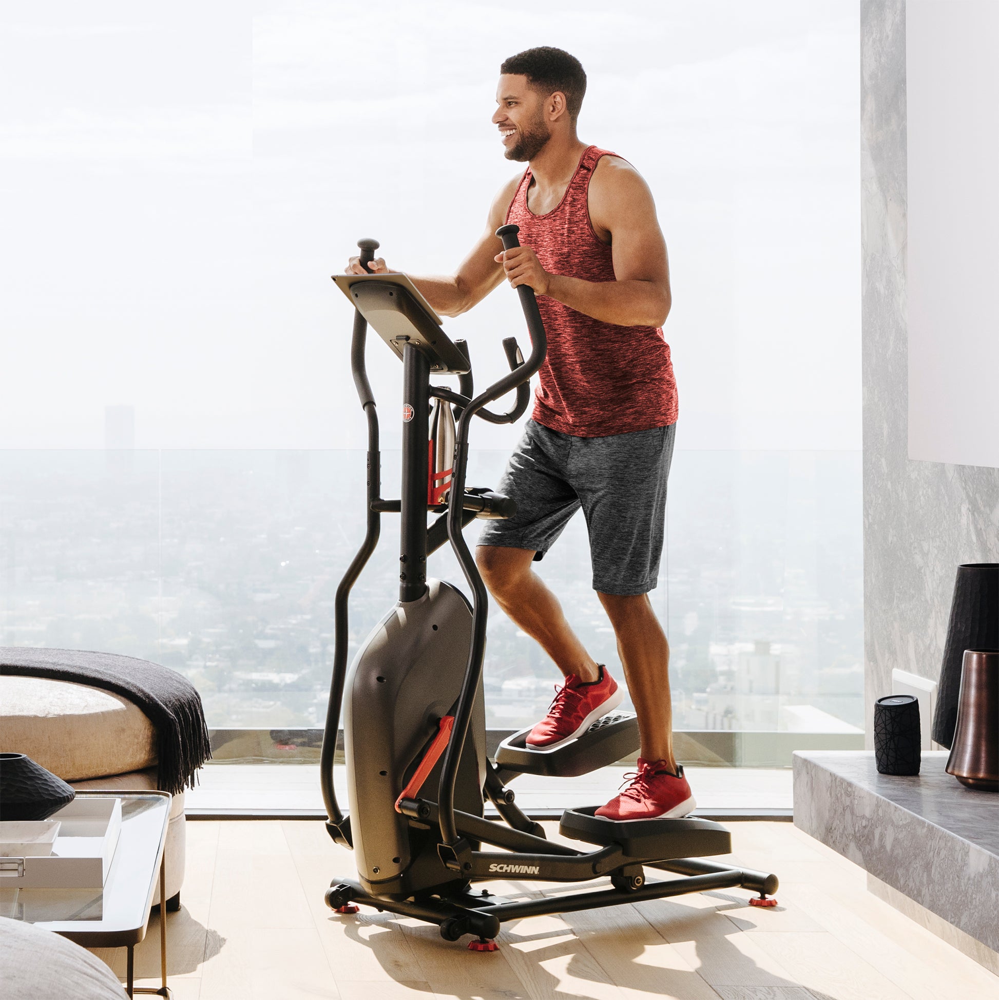 Man exercising on an elliptical machine in a modern living room.