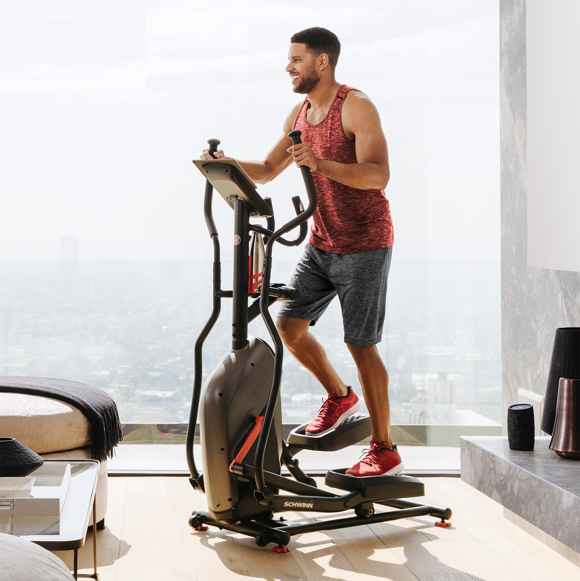 Man exercising on an elliptical machine in a modern living room.