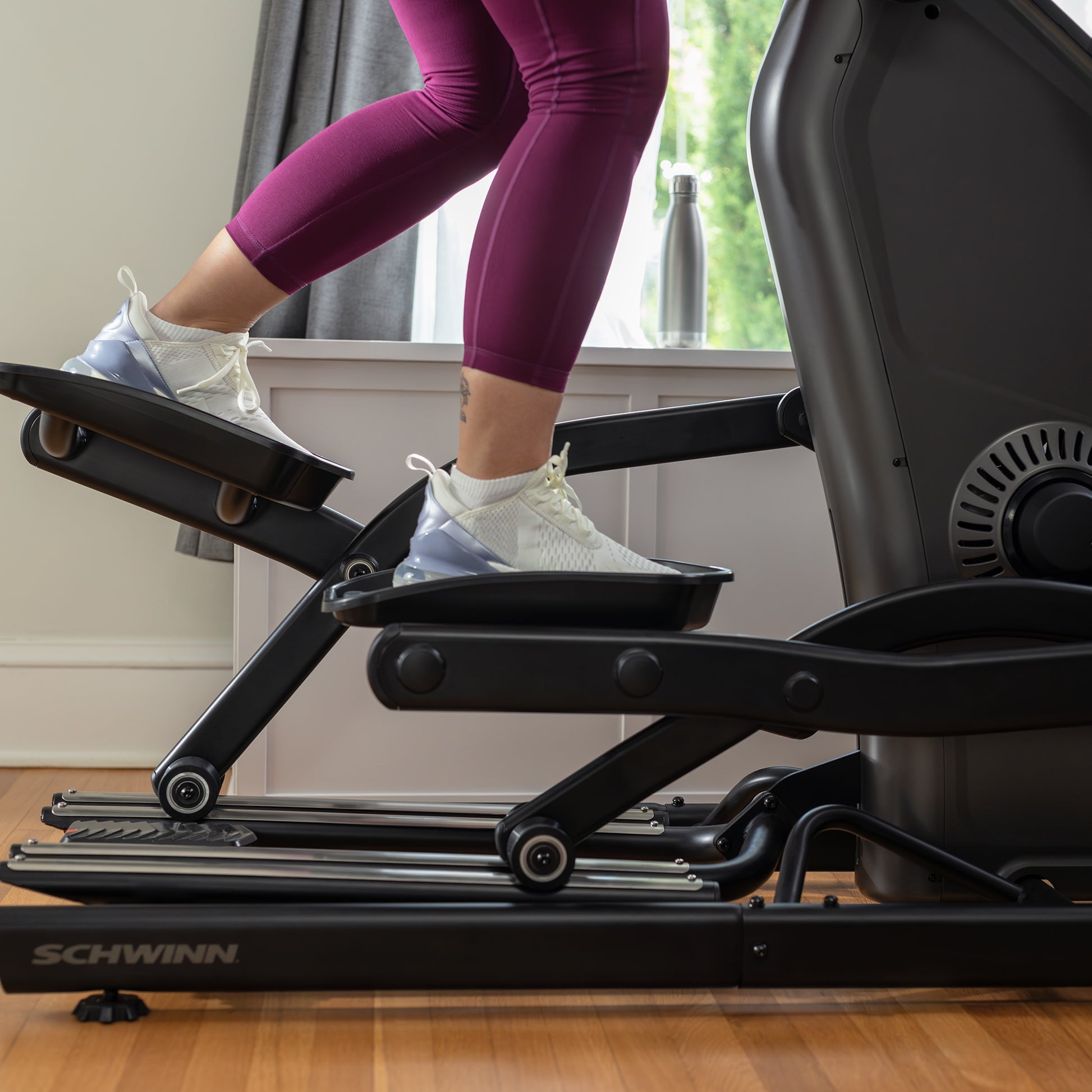 Person using a Schwinn elliptical machine indoors.