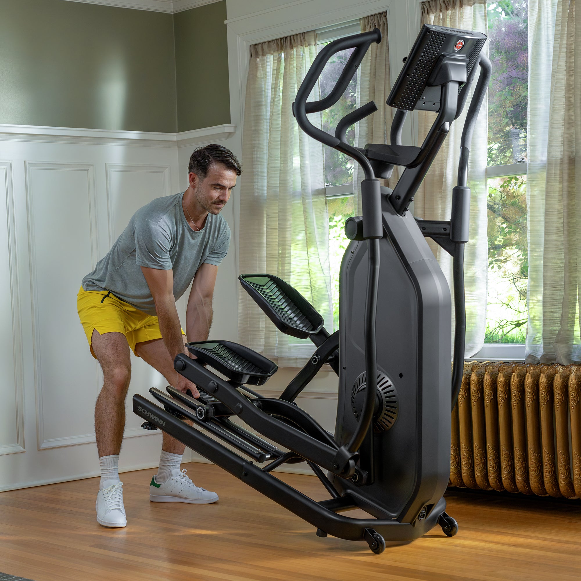 Man adjusting an elliptical machine in a home setting