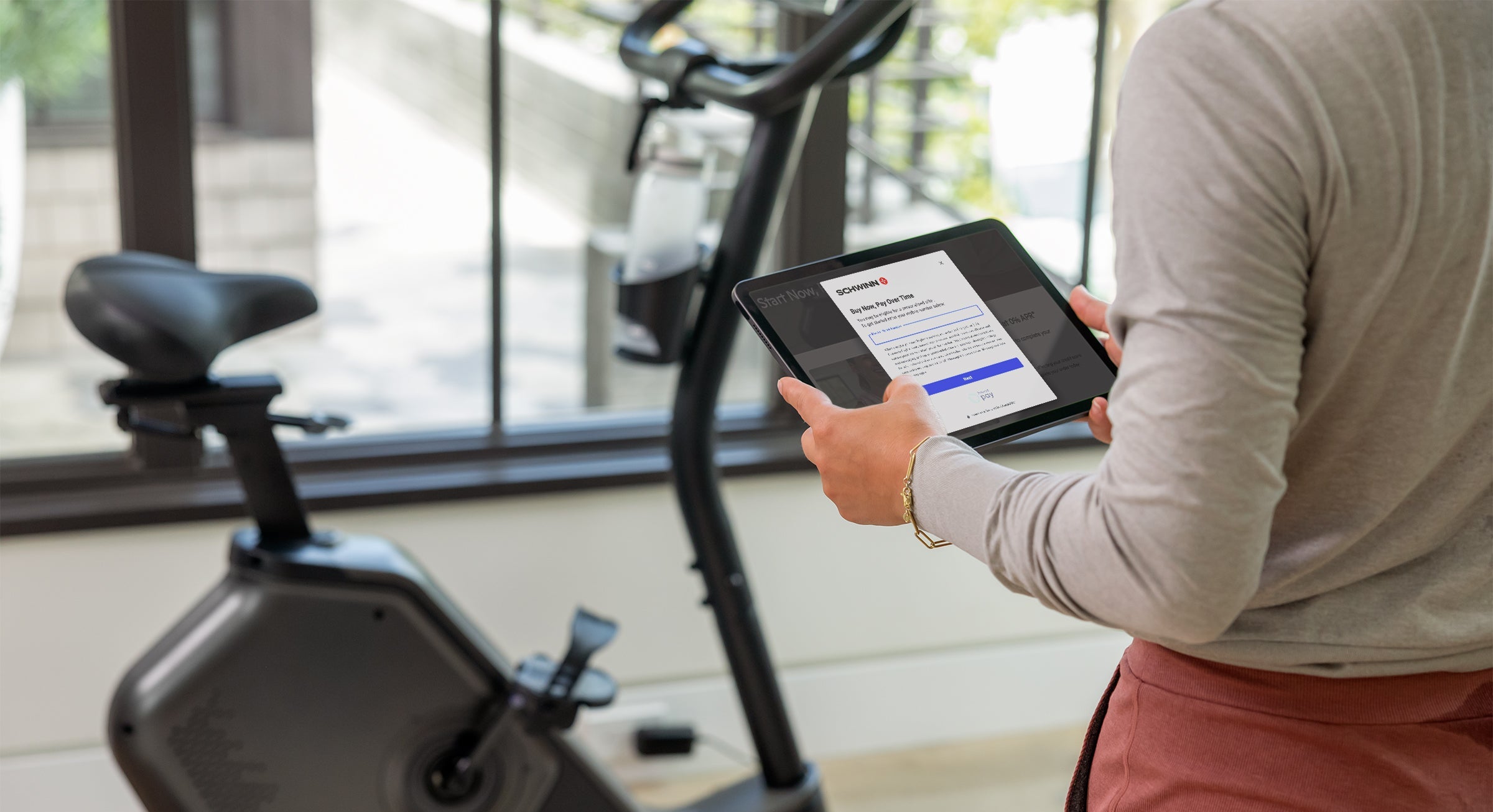 Person using a tablet in front of an exercise bike indoors