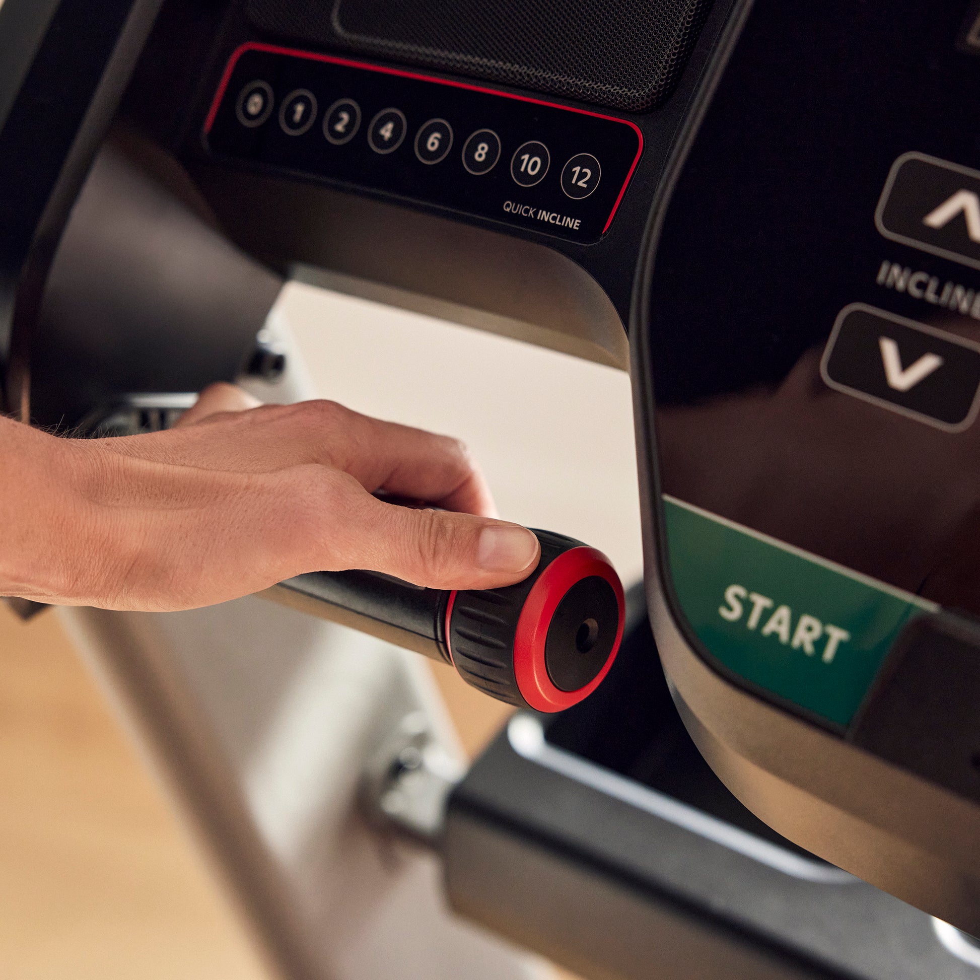 Hand adjusting a treadmill control knob with 'Start' button visible